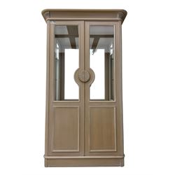 Contemporary display cabinet, moulded cornice above glazed panelled doors with central carved sunburst handles, mirrored back interior with lighting, lower enclosed storage compartment, raised on plinth base