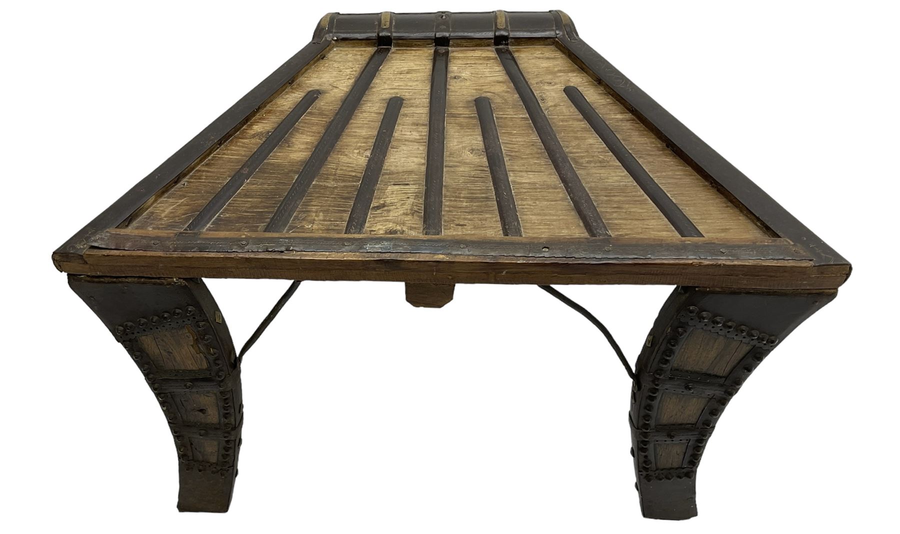 19th century Indian bullock / ox cart converted coffee table, trapezoidal top with applied metal decoration and iron stretchers, raised on three swept supports with stud decoration