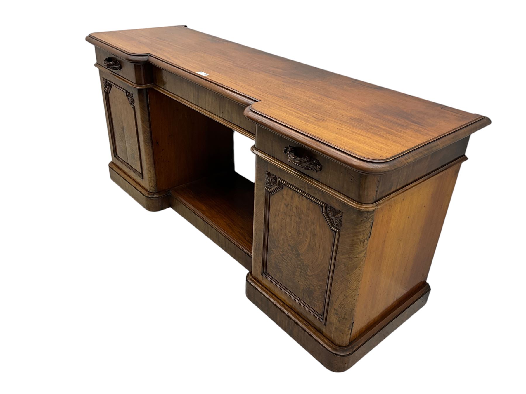 Mid-19th century figured mahogany sideboard, moulded reverse-break front, fitted with three drawers and two cupboards, carved faux bois handles, enclosed by panelled doors with book-matched veneers, applied geometric mouldings and scroll leaf decoration, on moulded plinth base 