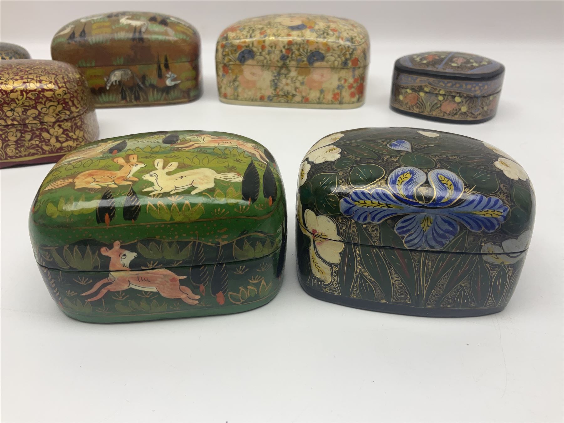 Nine lacquered boxes, all rectangular form, including russian examples decorated with animals within a stylized landscapes and example with flower decoration, largest H7cm, L11cm