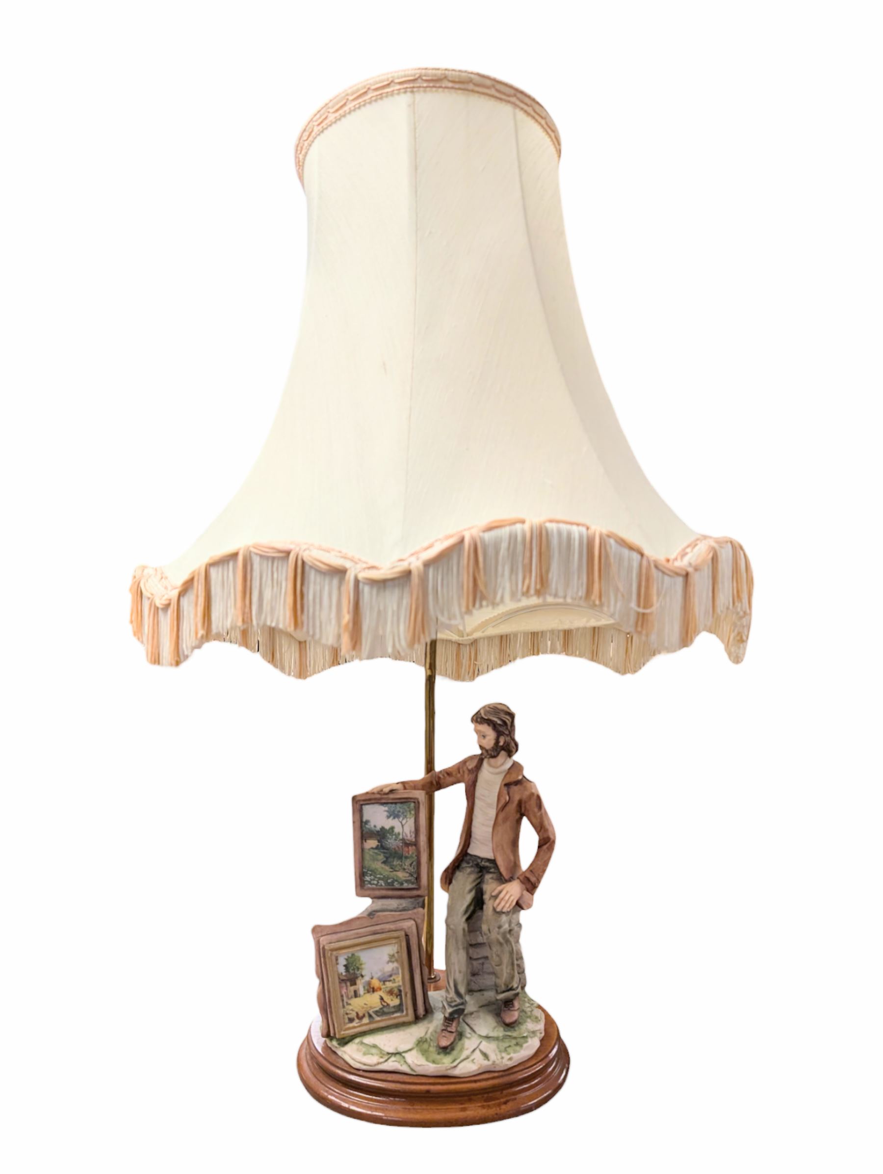 Capodimonte figural table lamp, modelled as an artist showcasing his work, with fabric tassel shade, H70cm