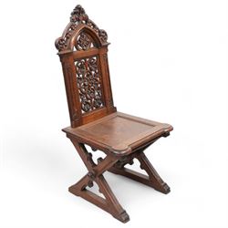 In the manner of Augustus Pugin - 19th century Gothic Revival oak hall chair, shaped pediment carved and pierced with foliate decoration, panelled back pierced with floral quatrefoil and scrolled decoration, panelled seat with moulded seat frame with projecting curved corners, on moulded X-framed supports united by turned and faceted stretcher, on sledge feet 