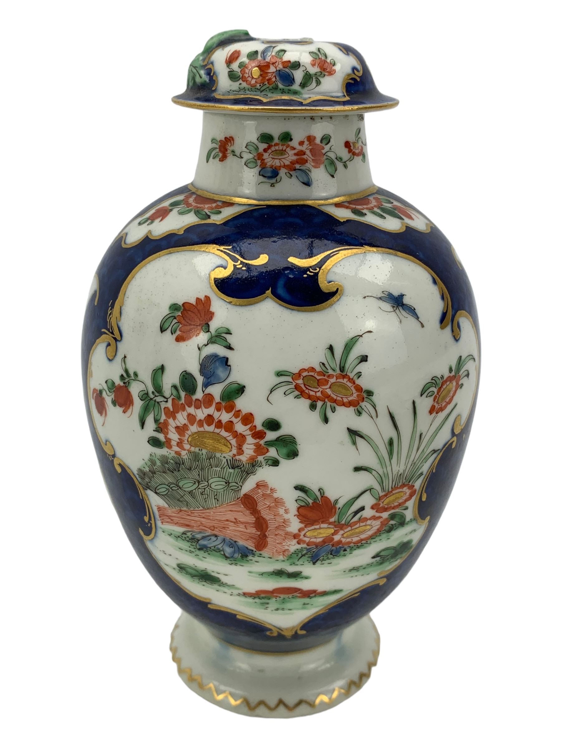 18th century Worcester tea caddy, of oval form and painted in the Kakiemon palette with reserves of flowers against a blue scale ground, H14cm together with a similar Worcester circular dish, painted with floral sprays, within a scalloped edge, blue crescent mark beneath, D19cm (2)