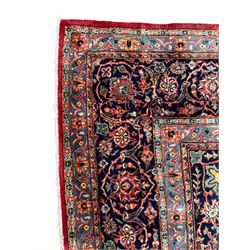 Persian Kashan crimson ground carpet, central rosette medallion on a field of trailing foliate branches decorated with palmettes, scrolling border with repeating plant motifs and flower heads, enclosed within floral pattern guard stripes