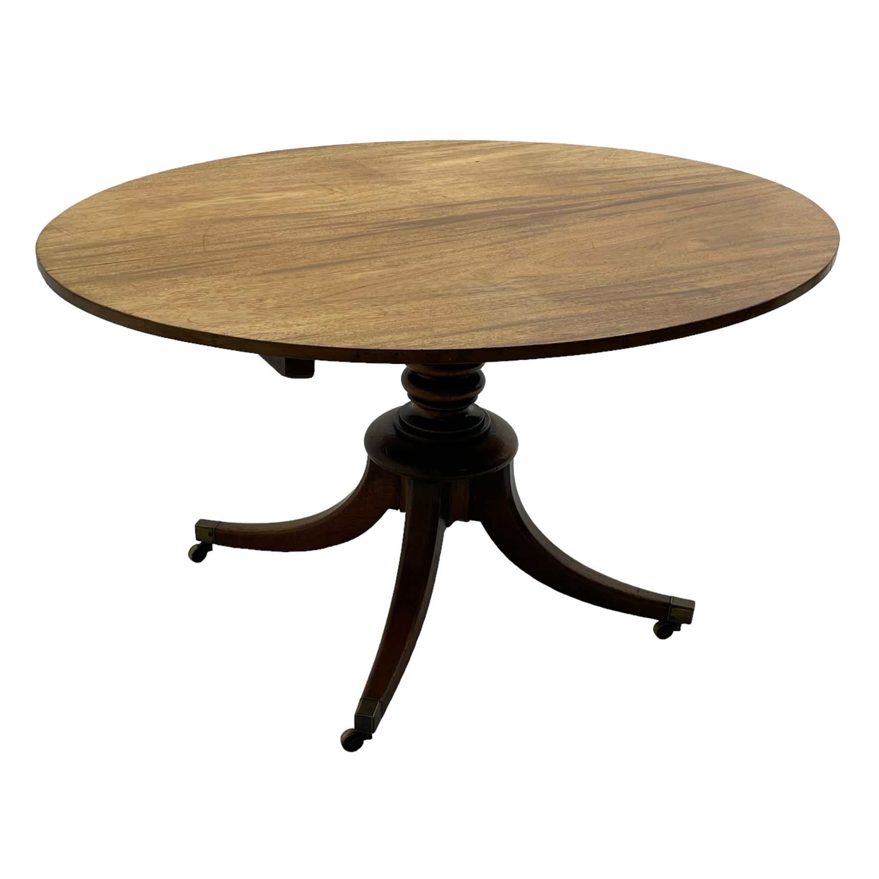 George III mahogany breakfast table, oval tilt-top on turned column with four splayed supports, fitted with brass cups and castors 