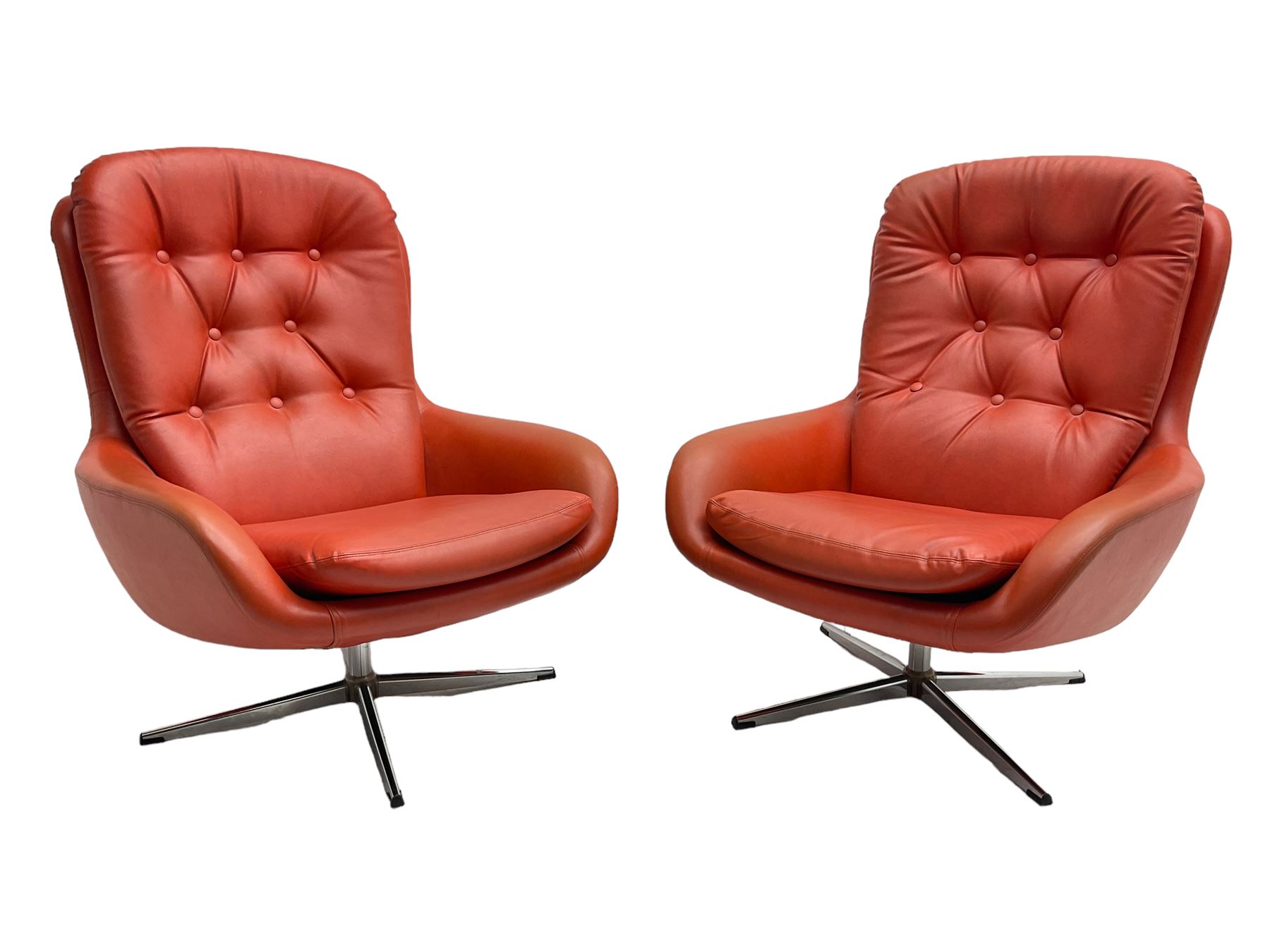 Pair mid-20th century circa.1974 swivel lounge chairs upholstered in buttoned red faux leather, on polished metal base