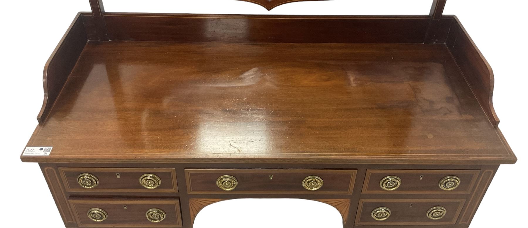 Edwardian inlaid mahogany kneehole dressing table, raised shaped oval bevelled mirror back, fitted with five drawers with banding and stringing, on square tapering supports with castors