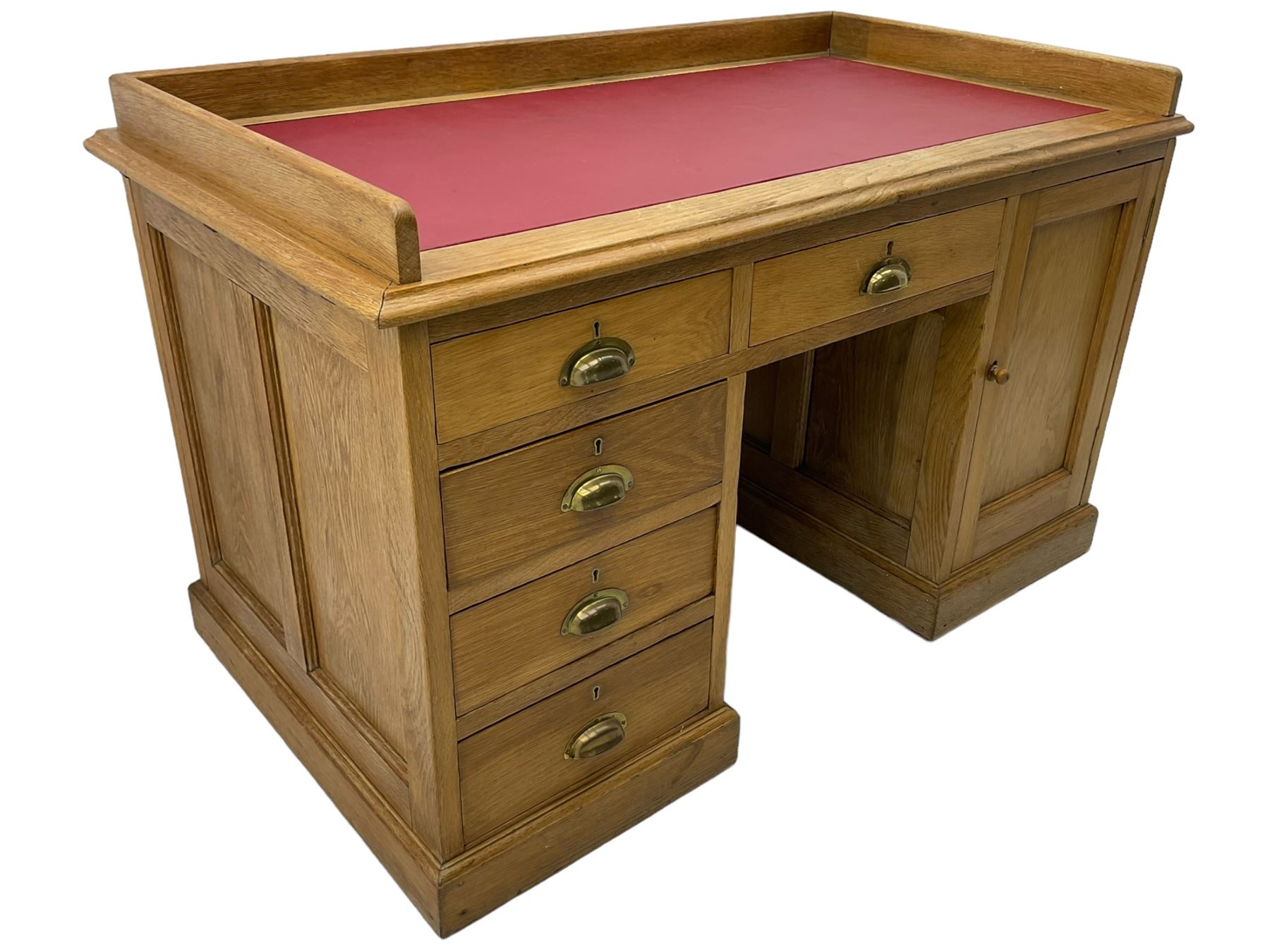 20th century oak desk, moulded rectangular top with raised back and inset leather writing surface, fitted with five drawers and single panelled cupboard, on moulded plinth base