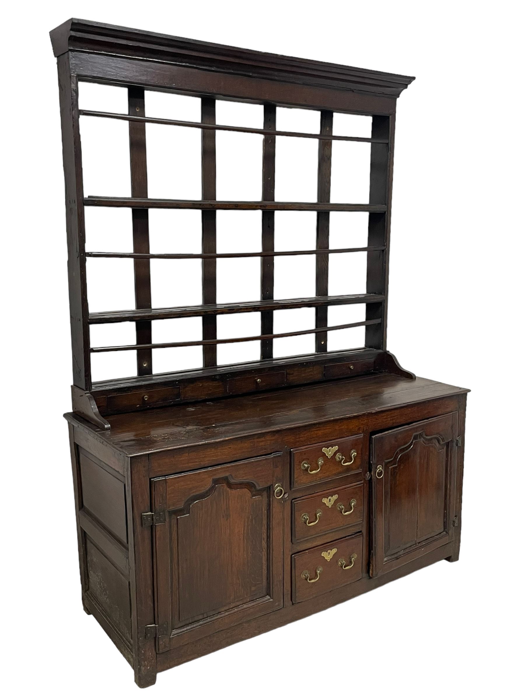 18th century oak dresser, projecting cornice over three heights plate rack with three small drawers, rectangular ovolo-moulded top over three central drawers and two flanking cupboards, enclosed by fielded panelled doors, on stile supports 