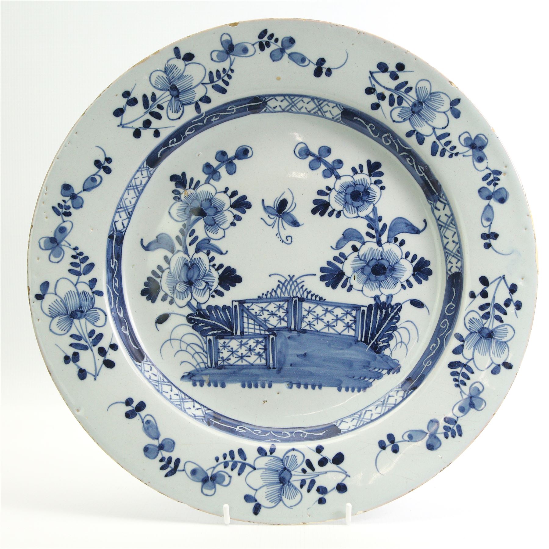 18th century English Delft charger, decorated in underglaze blue with a fence and peony, within a floral and geometric border, D35cm