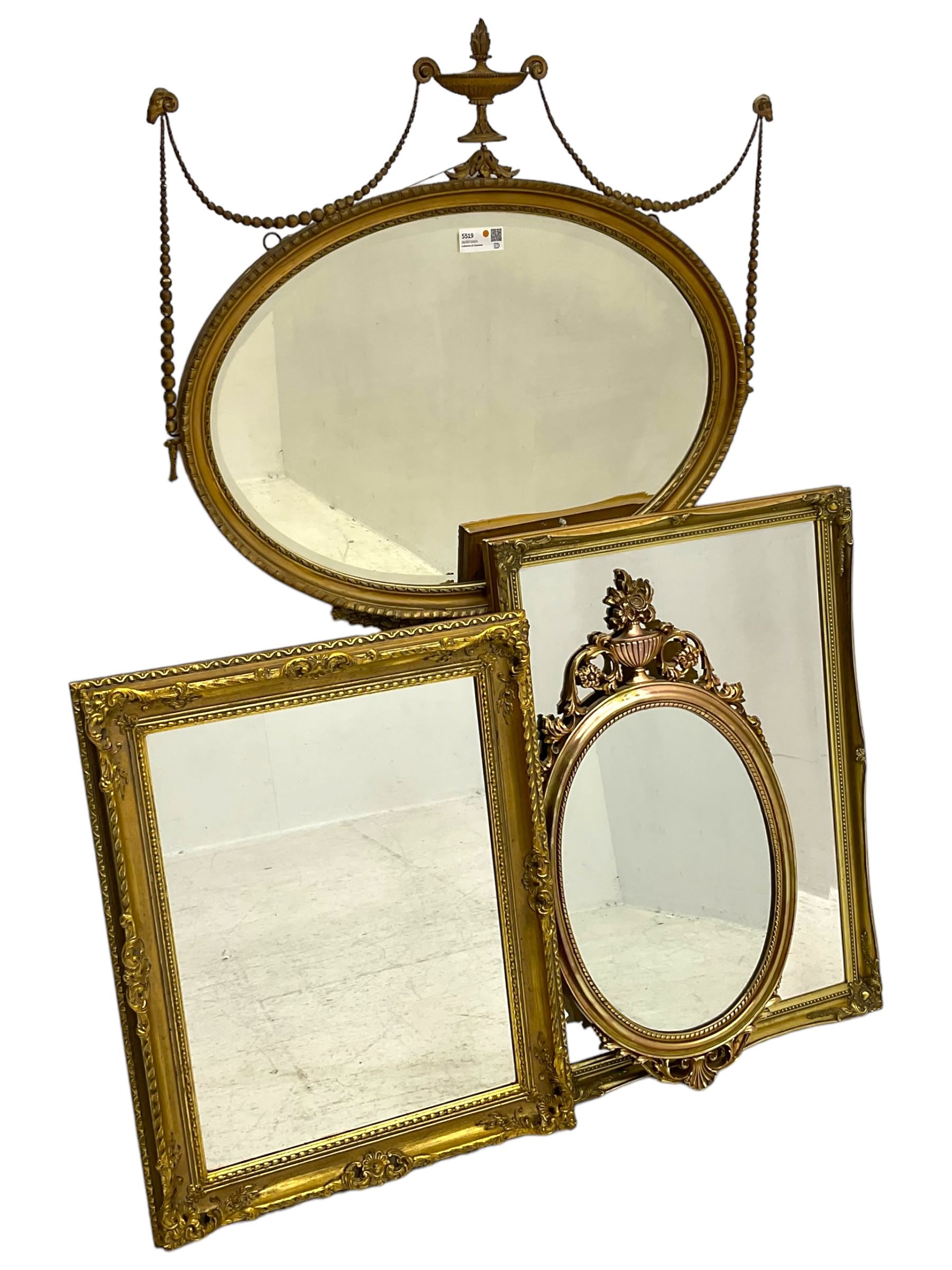 Regency revival style gilt framed oval mirror, the frame with laurel swags topped with urn and flame finial, beaded chain and ram's head motifs, bevelled glass pane; three additional gilt framed mirrors to include one oval and two rectangular (4)