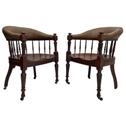 Pair of late Victorian walnut tub-shaped elbow chairs, the cushioned cresting rail upholstered in leather on spindle turned supports, dished saddle seat on turned supports