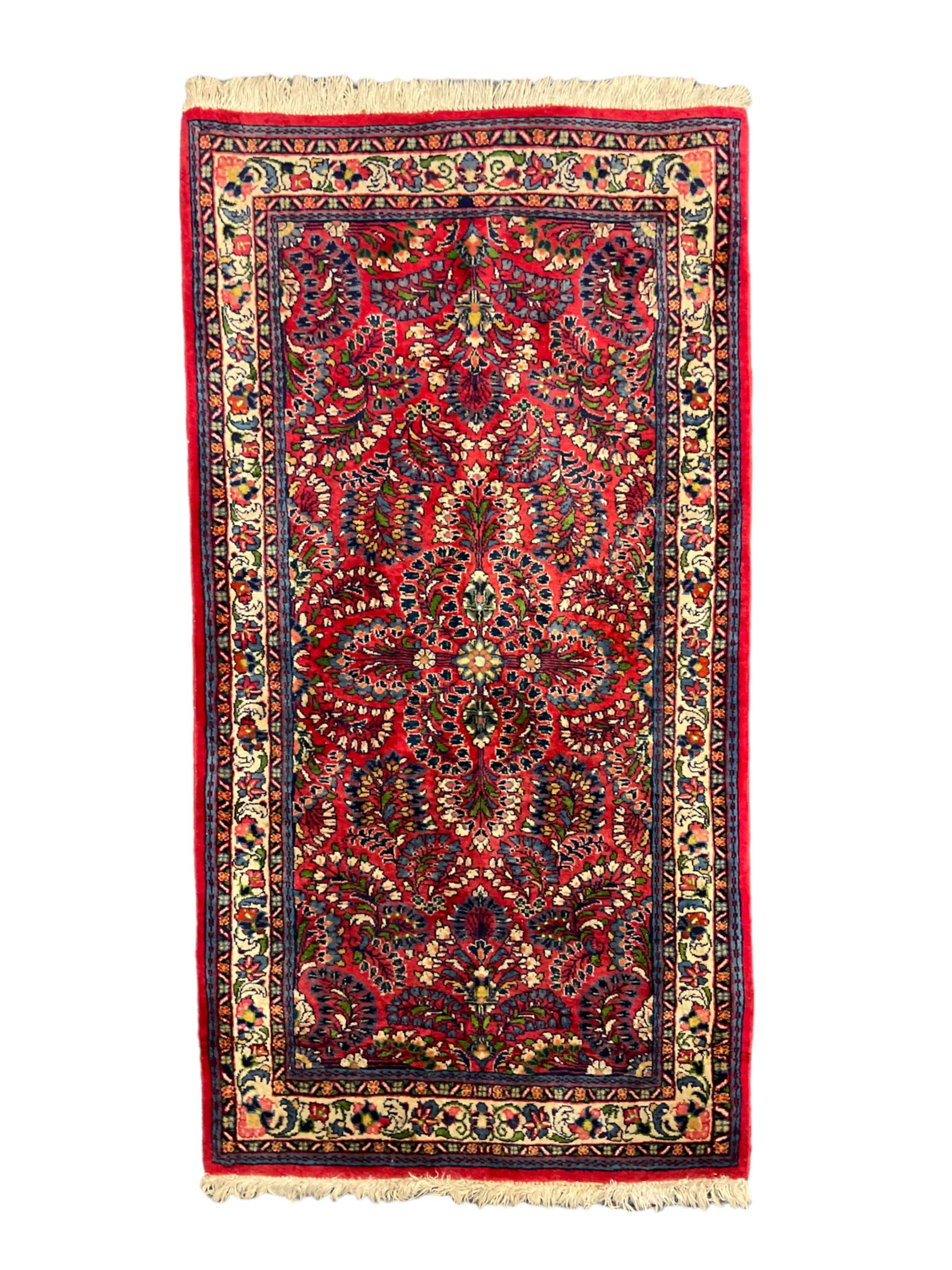 Small Persian red ground rug, the field decorated with an overall floral design, guarded ivory ground border decorated with trailing flower heads and foliage