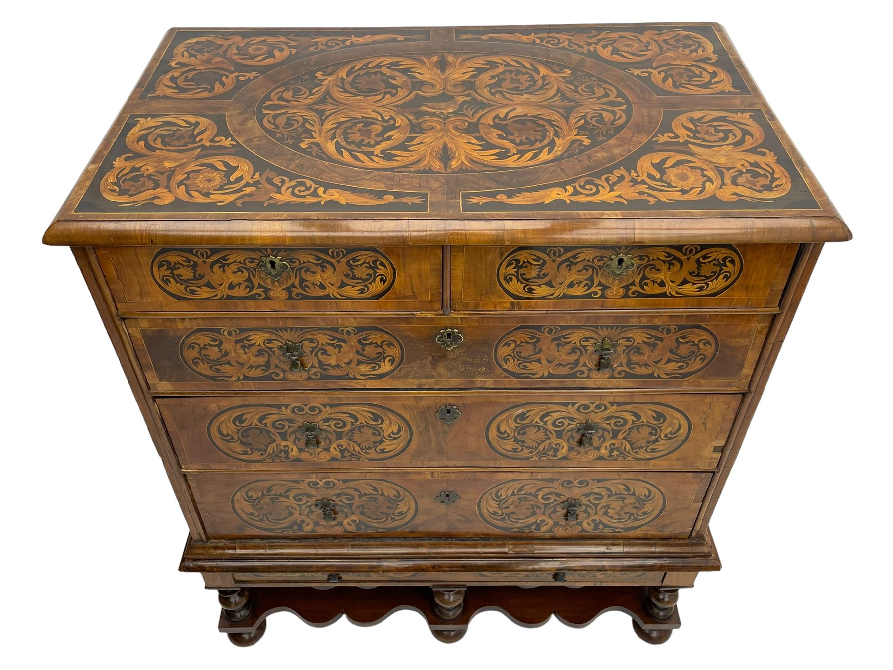 18th century inlaid walnut chest on stand, ovolo-moulded rectangular top inlaid with ebony panels each decorated with scrolling foliage, flower heads and birds, fitted with two short over three long drawers, the drawer fronts decorated with ebony panels enclosing curled leaf inlays, the base fitted with single drawer on turned supports united by waved stretchers, on turned bun feet 