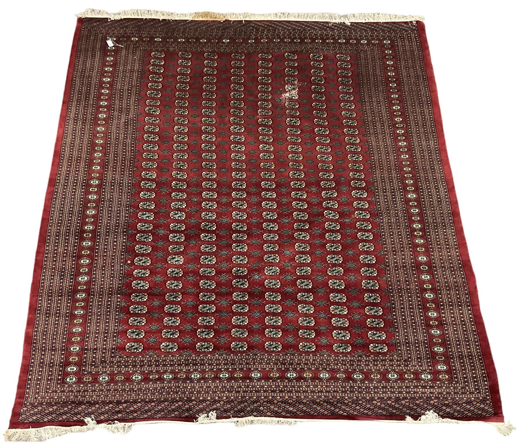 Large Persian Bokhara red ground carpet, the field decorated with eight rows of Gul motifs, wide multi-band borders decorated with repeating geometric motifs