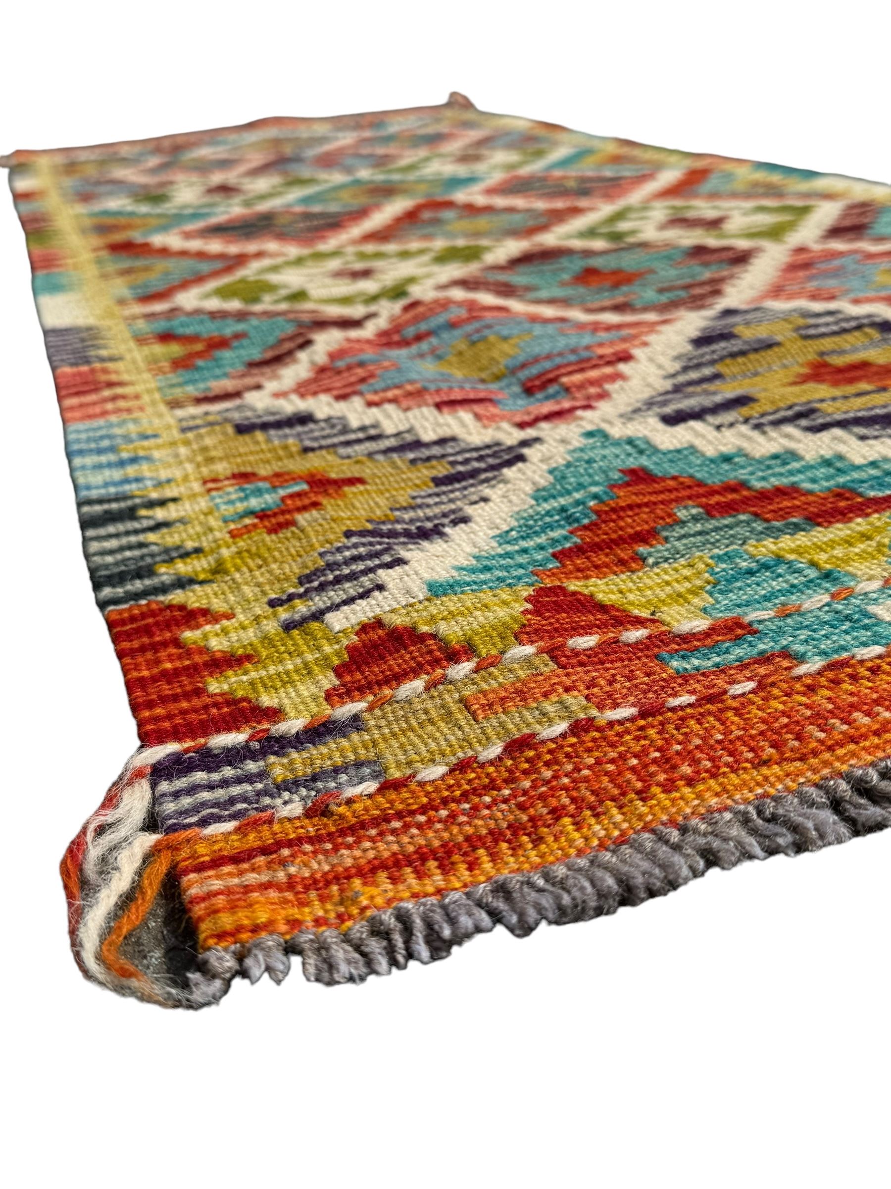 Chobi Kilim ground runner, the field decorated with a geometric pattern of coloured diamonds and triangles, each containing stylised motifs, the shorter ends enclosed by a plain border, and the longer sides with a multicoloured border

