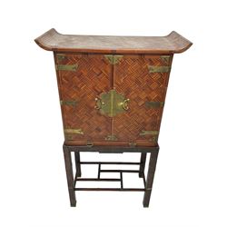 Chinese design bamboo and wood altar cabinet on stand, parquetry lattice-work bamboo, two doors with engraved metal fixtures enclosing drawers and shelf, fitted with slide, the stand pm square supports joined by a series of geometric stretchers