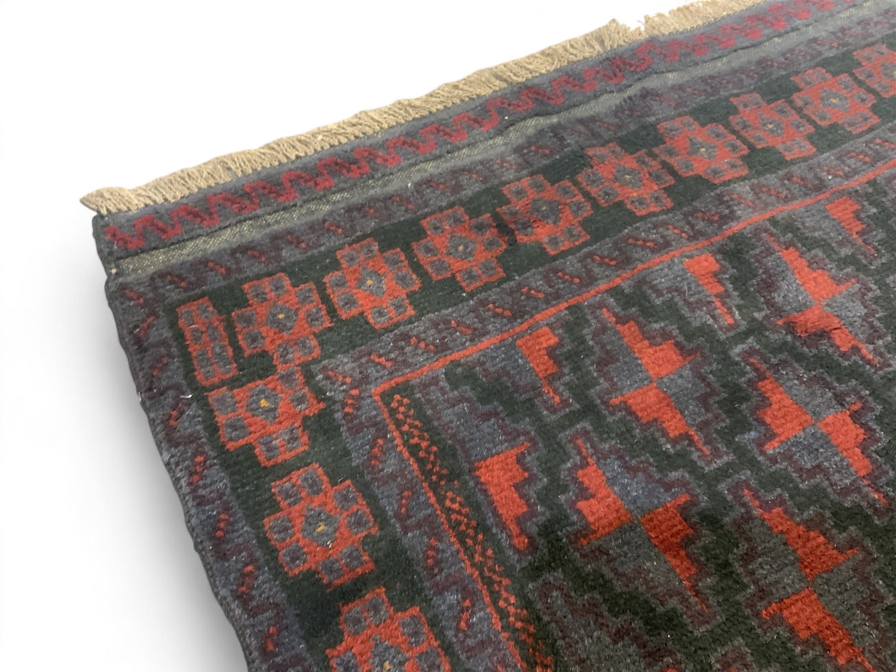 Baluchi indigo ground rug, the field decorated with all-over crimson and indigo lozenges, enclosed by geometric guard lines