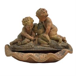 Terracotta garden fountain in the form of putti on a naturalist base, raised upon shell basin