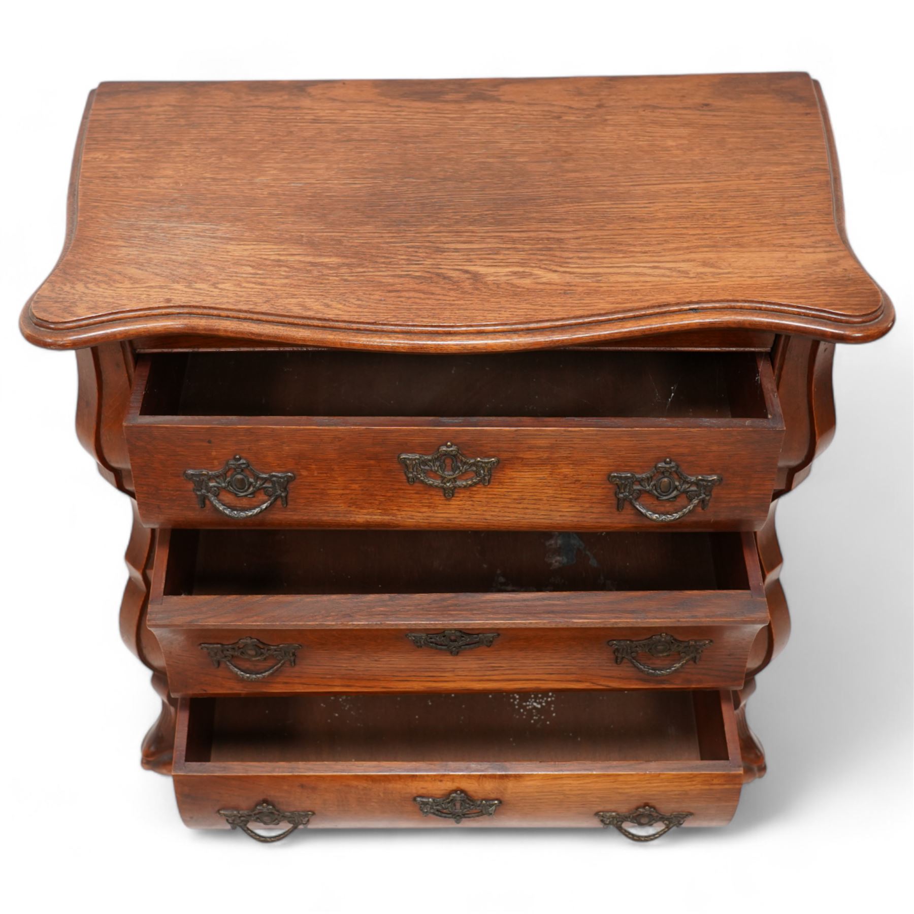 Early 20th century Dutch oak bombe chest, shaped rectangular top with moulded edge, fitted with three drawers flanked by moulded uprights, on hairy ball-and-claw feet