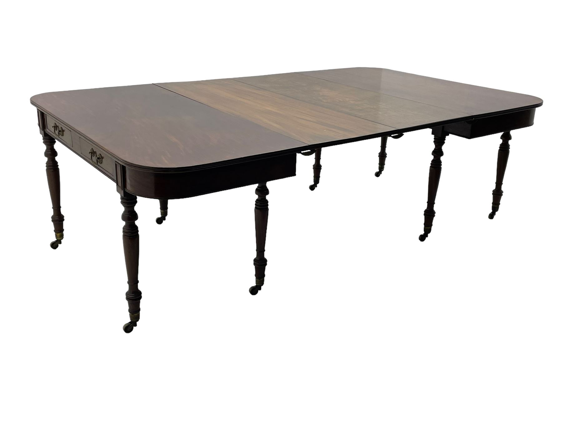 George III mahogany extending dining table, reed moulded rectangular top with rounded corners, two D-ends each fitted with two drawers, two additional leaves, on turned supports with ribbed brass cups and castors 