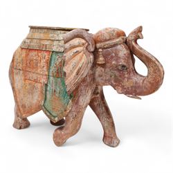 Early 20th century Indian hardwood and polychrome Elephant jardiniere stand, decorated with a headdress and vibrant saddle cloths, surmounted by an octagonal shaped saddle, with overall craquelure finish