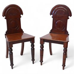 Pair of late Victorian mahogany hall chairs, arched cresting over foliate carved decoration and carved roundel back, chamfered seat over ring turned front supports 