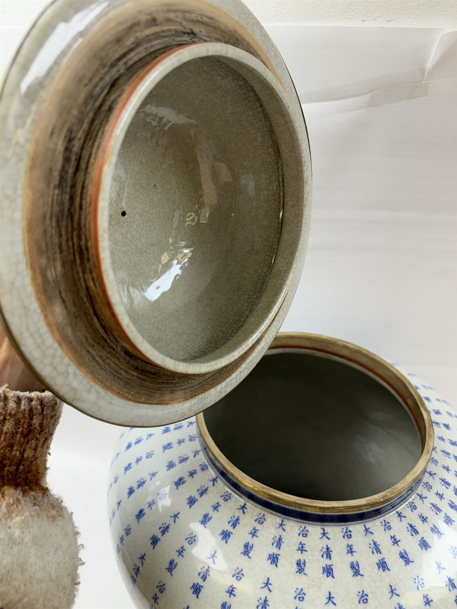 Large Oriental design ginger jar and cover, of squat baluster form with domed cover, decorated in blue with Chinese characters against a white crackle glaze ground, the cover, neck and foot rim with applied brass band, with character mark beneath, H43cm