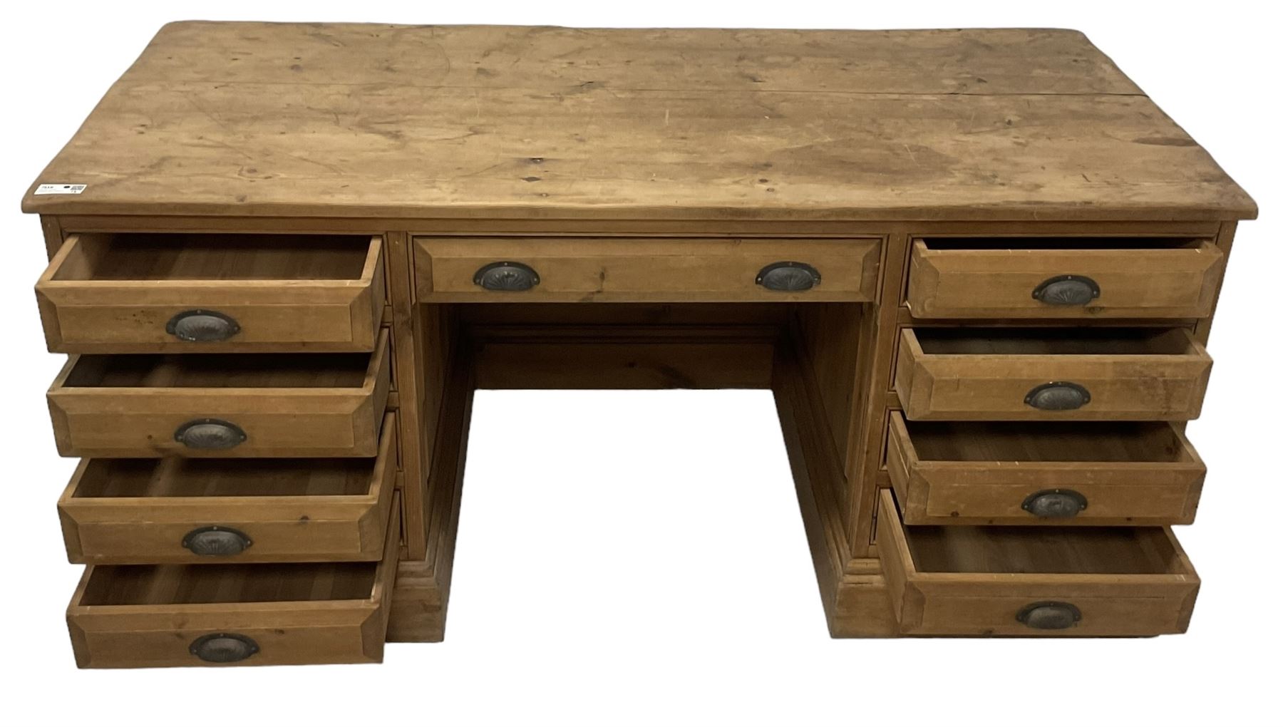 20th century waxed pine kneehole desk, rectangular top over nine drawers with cup handles, on moulded plinth base