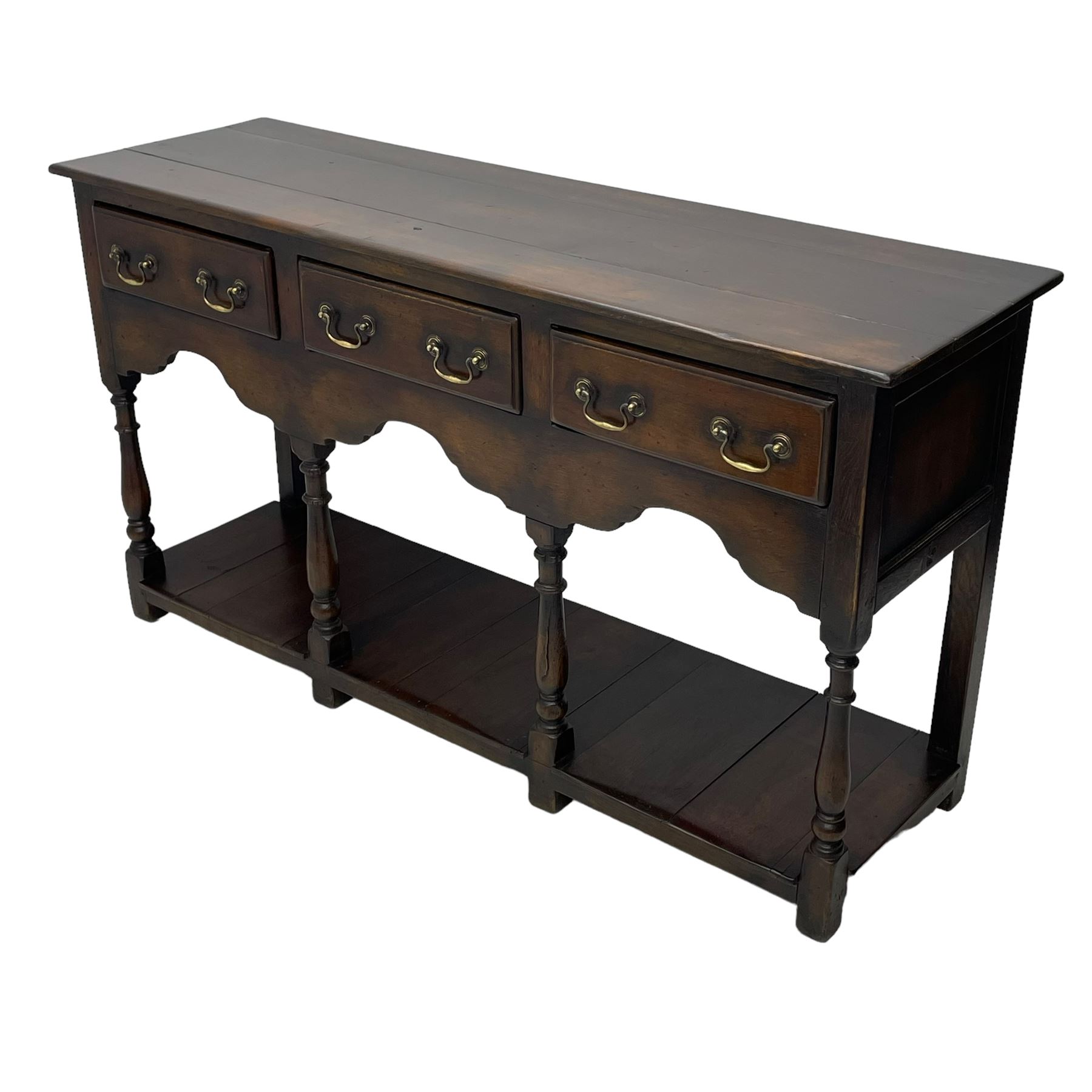 Georgian design oak dresser base, rectangular three plank top over three drawers and shaped apron, moulded drawer fronts with brass swan neck handles and circular plates, turned supports on panelled pot board base