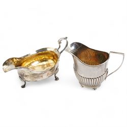 George III silver sauce boat with leaf capped scroll handle and shaped supports, Newcastle assay Maker John Langlands I and John Robertson I and a silver cream jug Birmingham 1907 