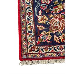 Persian Kashan red ground rug, the field decorated with a central floral medallion surrounded buy scrolling vine motifs and palmettes, the main border featuring a series of stylised floral motifs against a dark blue ground, enclosed by multiple guard stripes with alternating floral and geometric designs