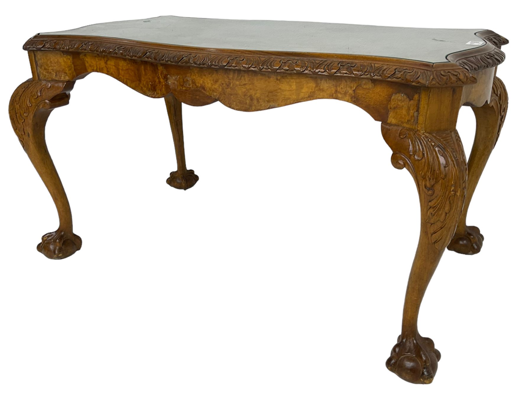 Mid-20th century figured walnut serpentine coffee table, inset glass top and foliate carved edge, raised on cabriole supports with acanthus moulded knees and ball and claw feet