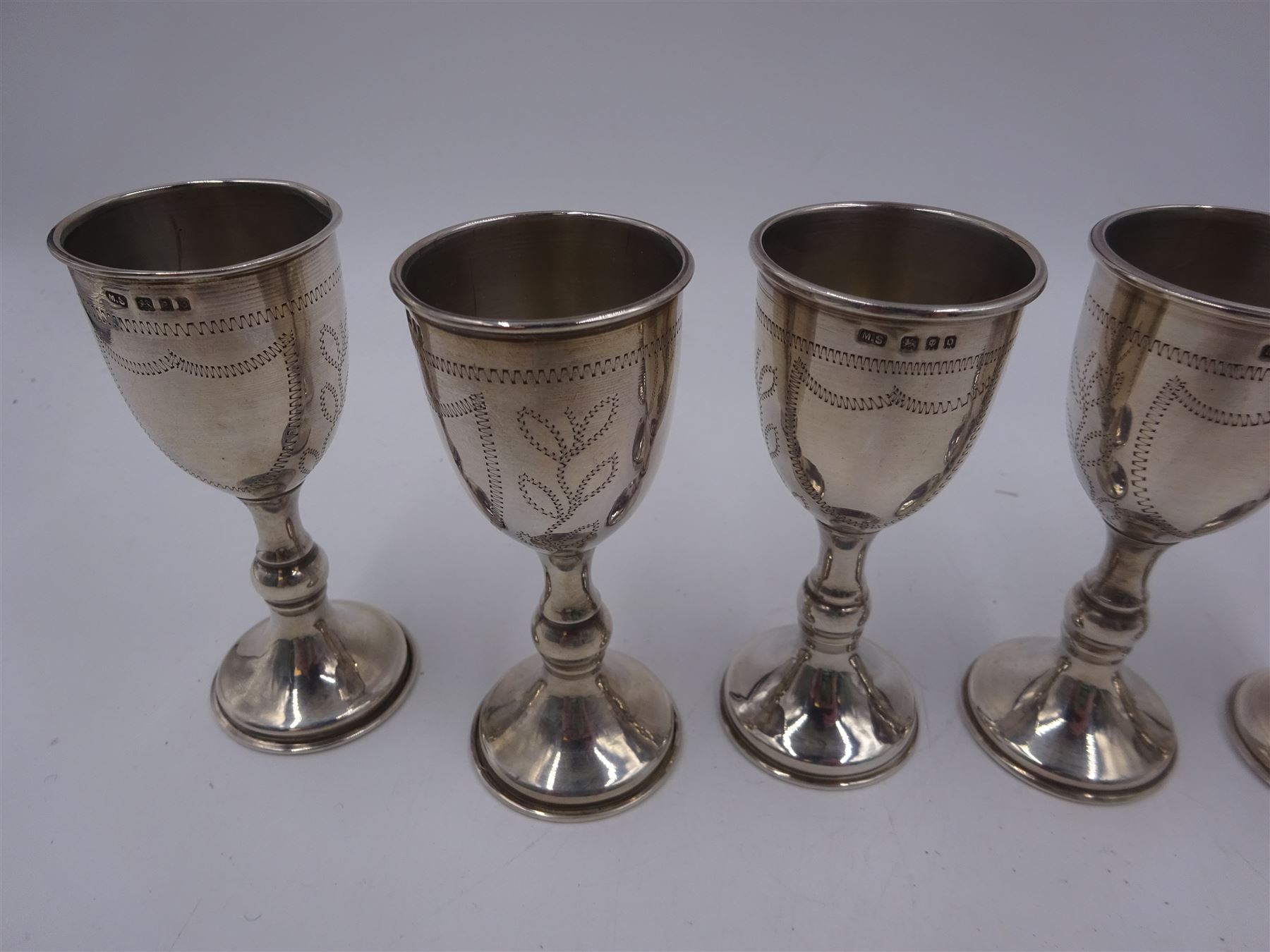 Set of six 1920s silver Kiddush cups, of goblet form with knopped stem, and engraved foliate detail, hallmarked London 1929, maker's mark M.S, H9cm