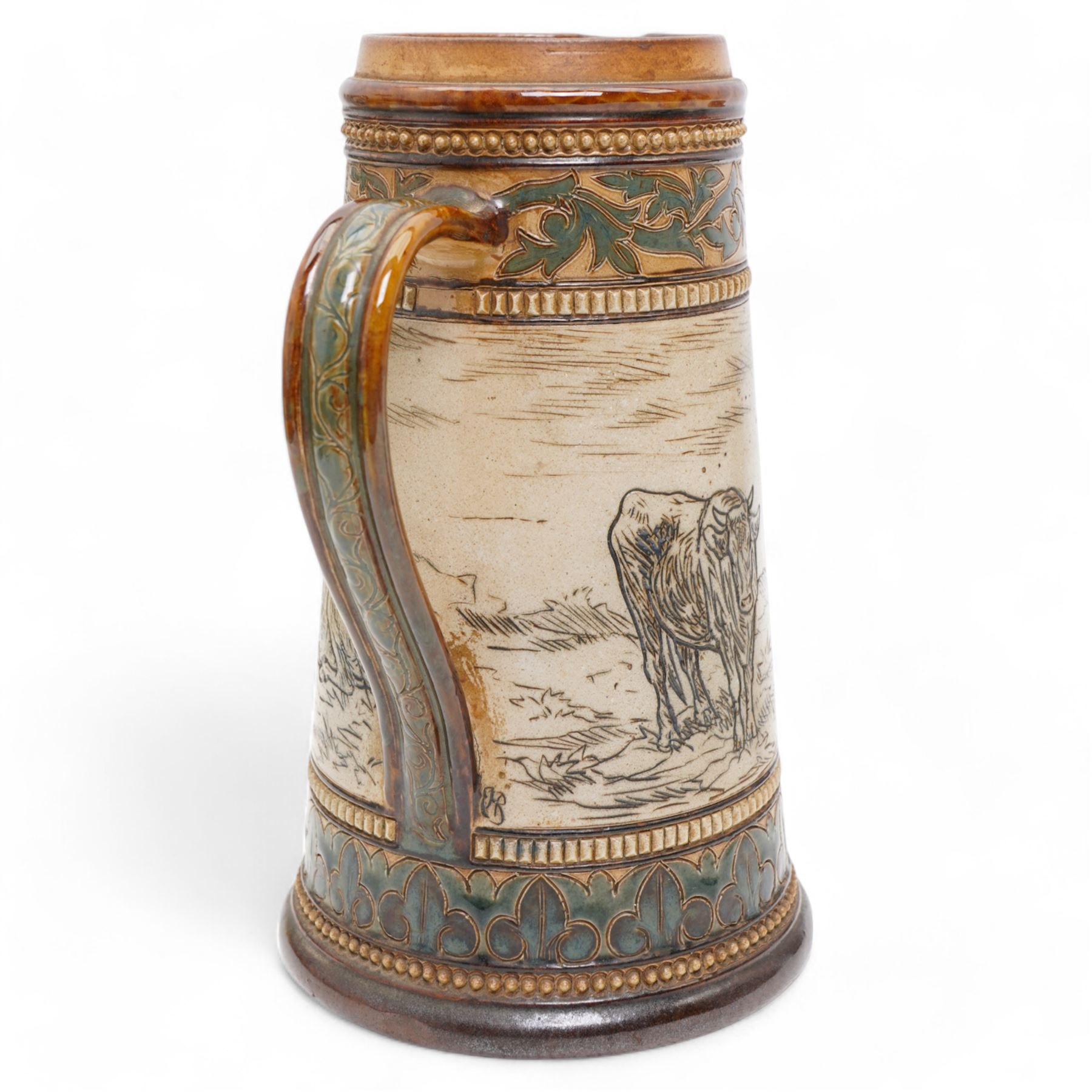 Late 19th century Doulton Lambeth sgraffito jug and beaker by Hannah Barlow, decorated with bands of cattle in landscapes between foliate boarders, with impressed and incised marks beneath, including monogram H24cm (2)