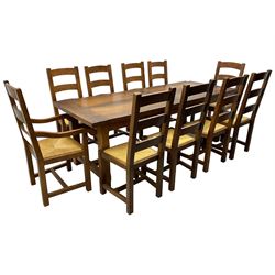 Antix Furniture - oak extending refectory dining table, rectangular plank top with two additional leaves and two drawers to the longer side, on square supports connected by H-stretcher; set of ten (8+2) ladder back dining chairs with rush seats