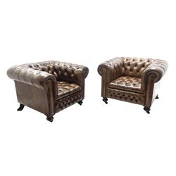 Large pair of Country House chesterfield club armchairs of generous proportions, upholstered in deeply buttoned brown leather, turned front supports with castors, rear splayed supports