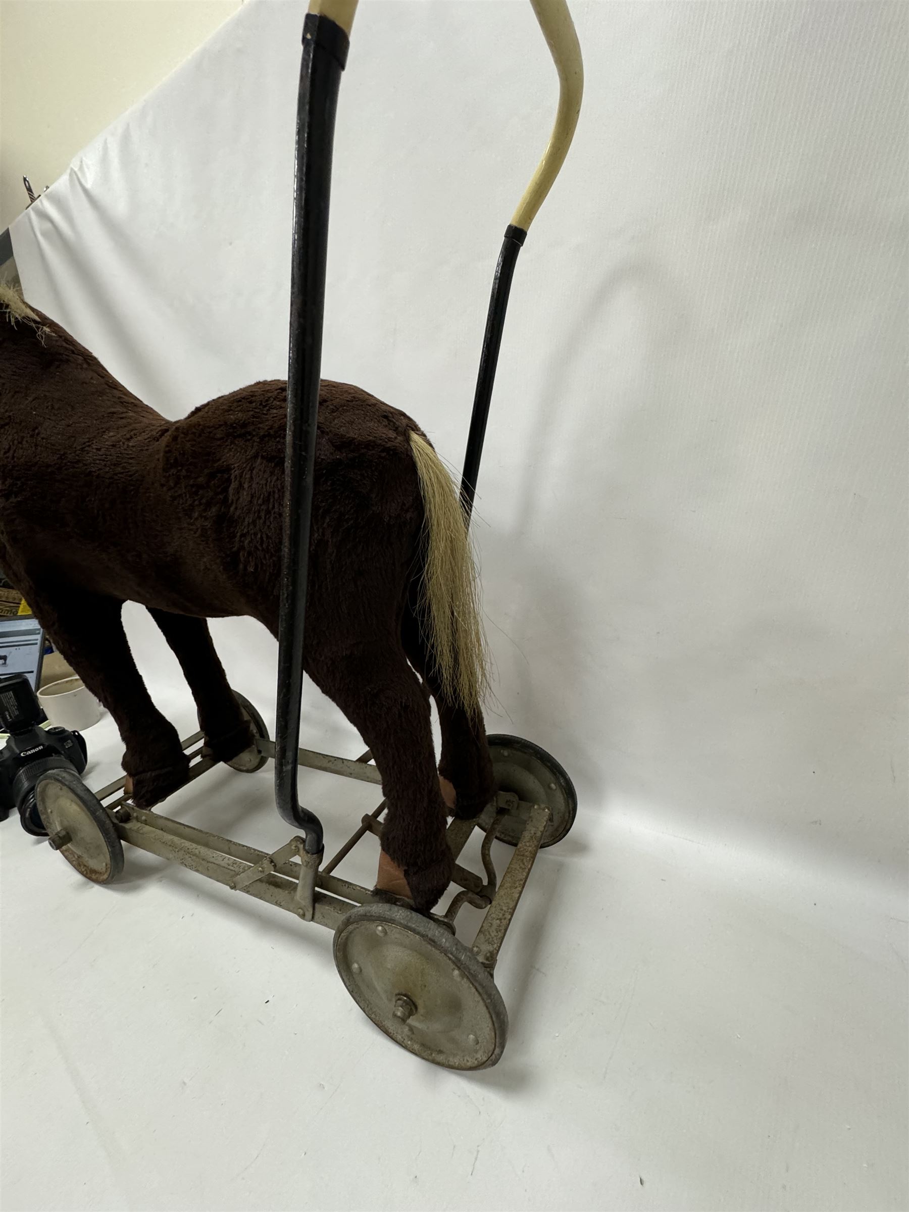 1920s/30s Panurge Pets push-a-long horse, with brown mohair body and white face, horse hair mane and tail and leather hooves, mounted upon a metal with rubber and metal wheels, including handle H71cm