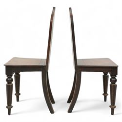 Pair of 19th century carved oak hall chairs, the arched back carved with moulded scalloped decoration with a central applied shield motif, canted panelled seat over turned octagonal supports