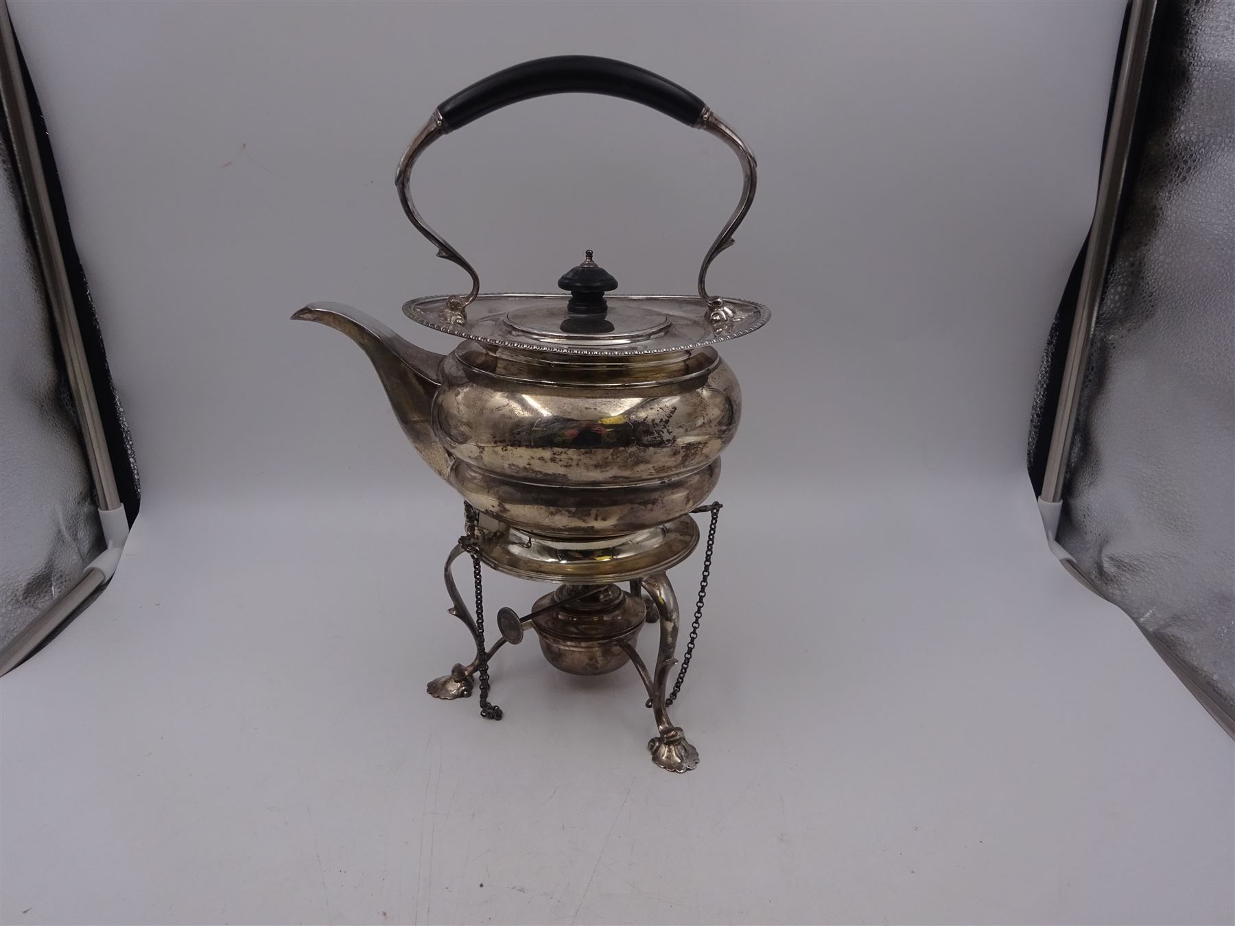 Early 20th century silver spirit kettle and burner, of oval form, with oblique gadrooned rim, engraved crest and ebonised handle and finial, the stand upon three scrolling pad feet, hallmarked Goldsmiths Silversmiths Company, London 1913, total H31cm