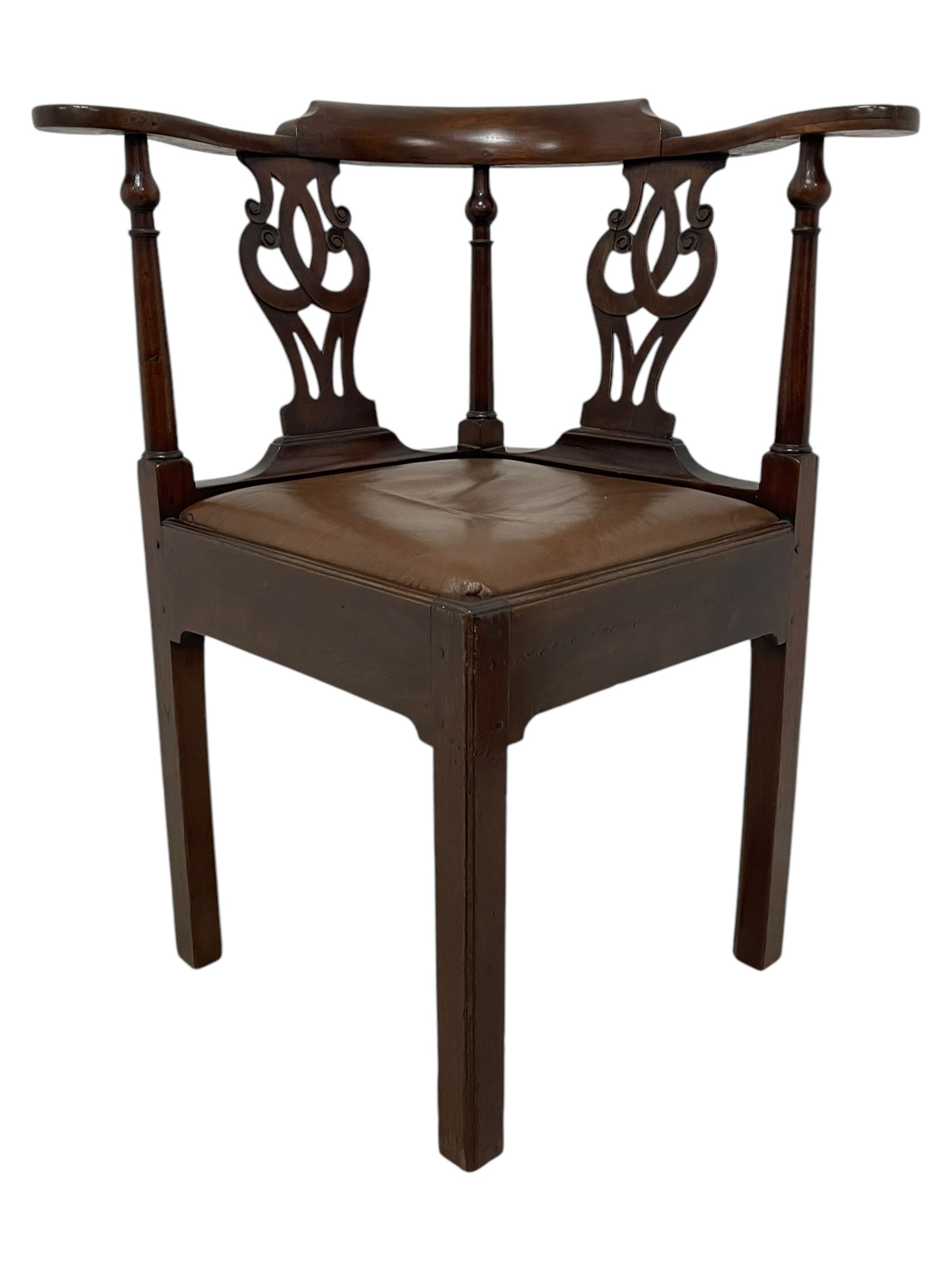 George III mahogany corner elbow chair, curved back rest and shaped arms with scroll carved terminals, on turned supports and pierced scroll carved interlaced splats, drop-in seat upholstered in brown leather, on square supports with inner chamfer and outer moulding 