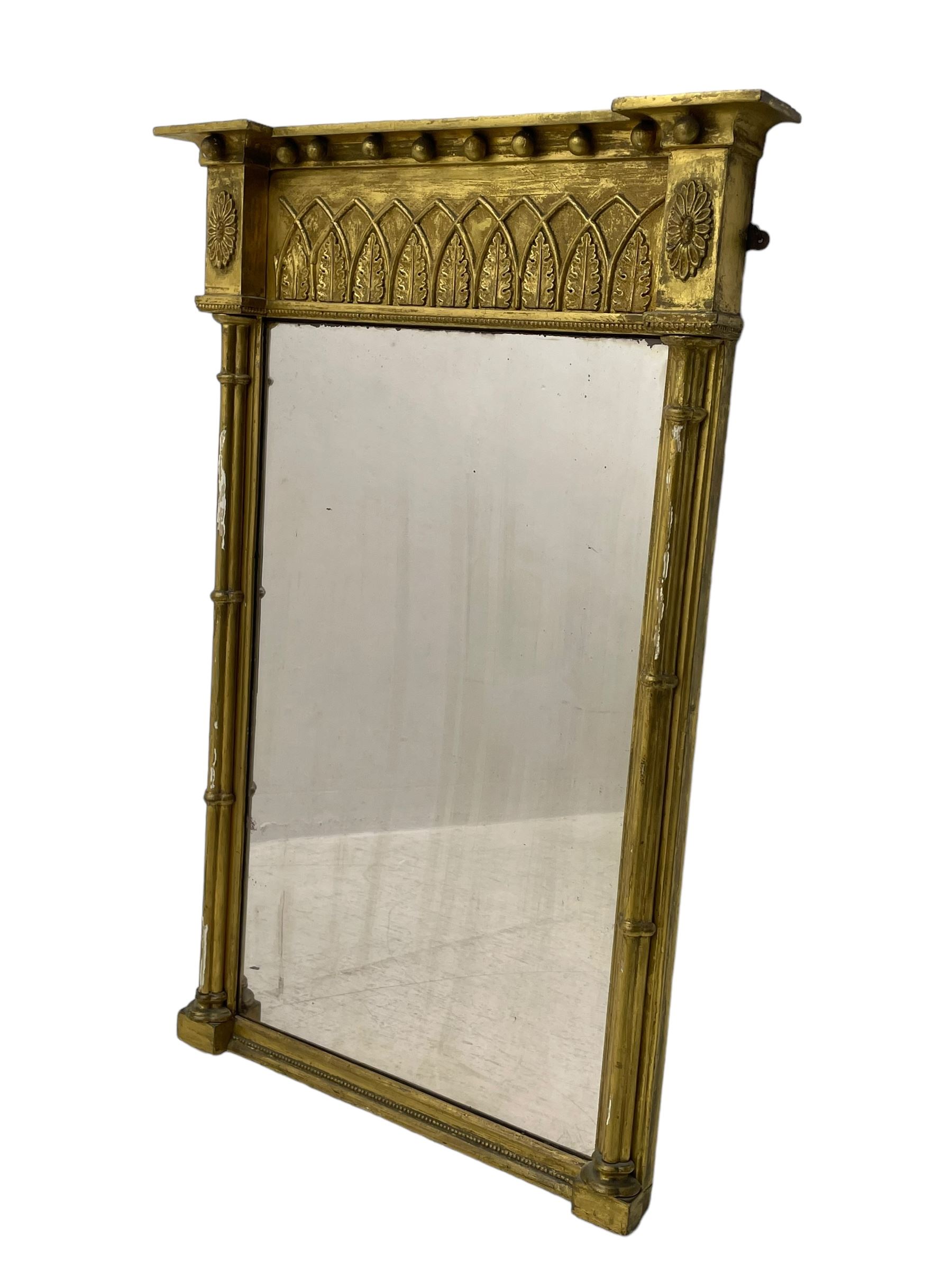 Regency giltwood and gesso pier mirror, projecting cavetto cornice with ball mounts, the frieze decorated with pointed arcade and foliate motifs, plain mirror plate enclosed by cluster column pilasters 