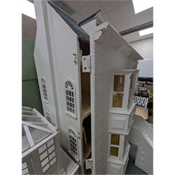 Large three storey modern dolls house, painted white with latticed windows, grey roof and metal fencing, with decorated interior, together with two dolls house garden rooms and two conservatories