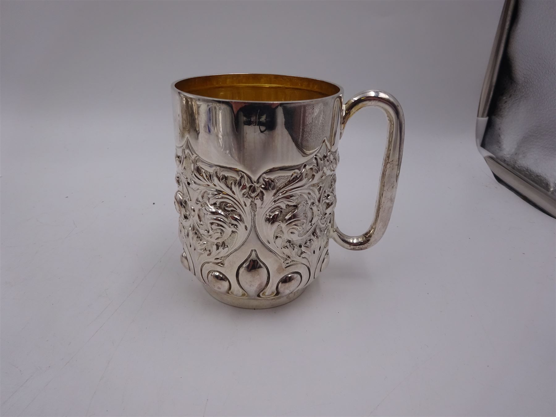 Late Victorian silver christening mug, with C handle and gilt interior, the body profusely embossed with floral and foliate decoration, hallmarked Atkin Brothers, Sheffield 1897, H10cm