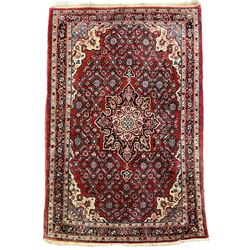 Persian design crimson ground rug, the field decorated with central floral pole medallion and surrounded by foliate patterns with matching spandrels, guarded border with repeating palmette motifs