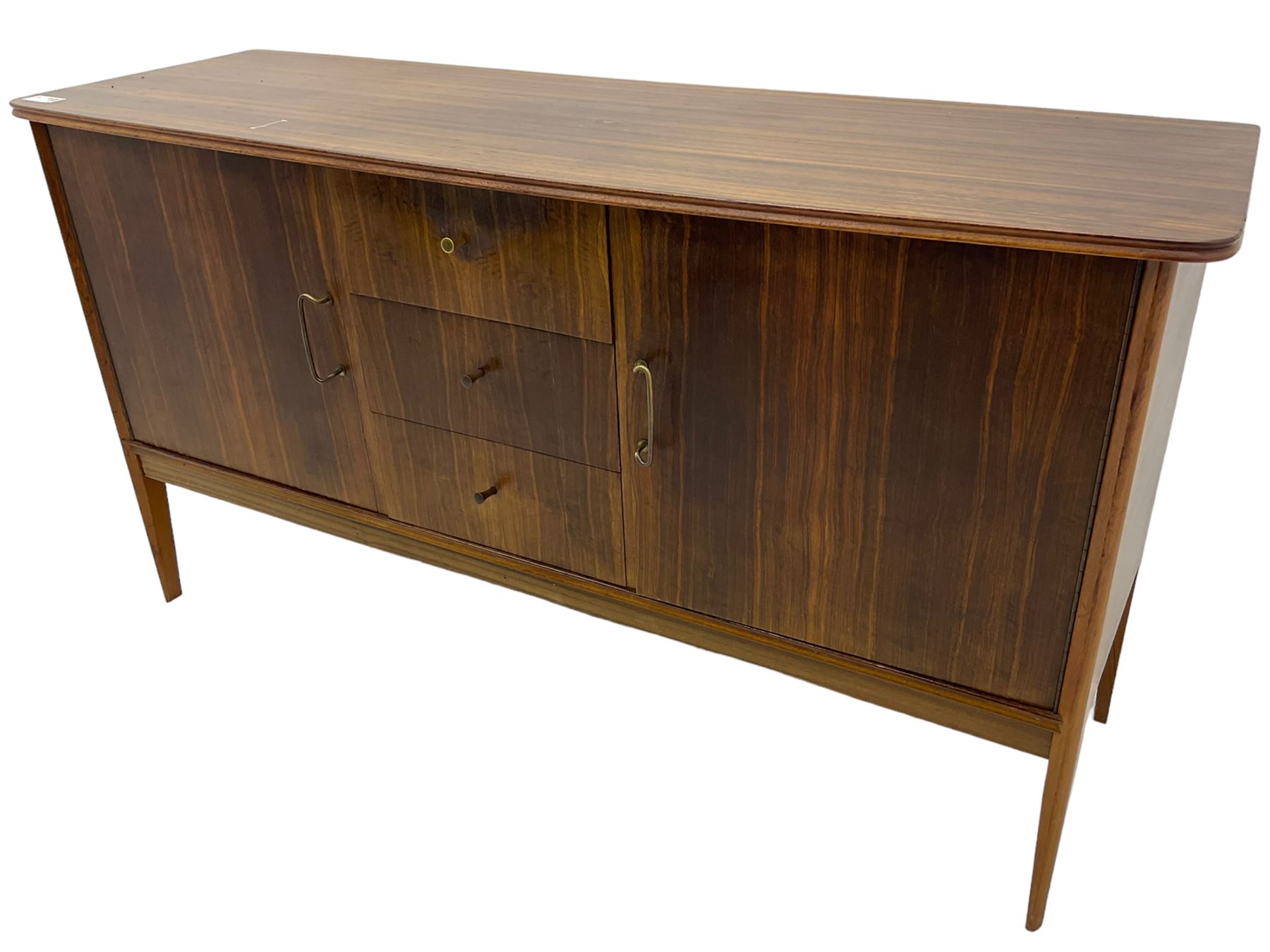 Mid 20th century teak sideboard, rectangular top with rounded corners over three central drawers, flanked by two cupboard doors enclosing shelves, raised on tapered supports