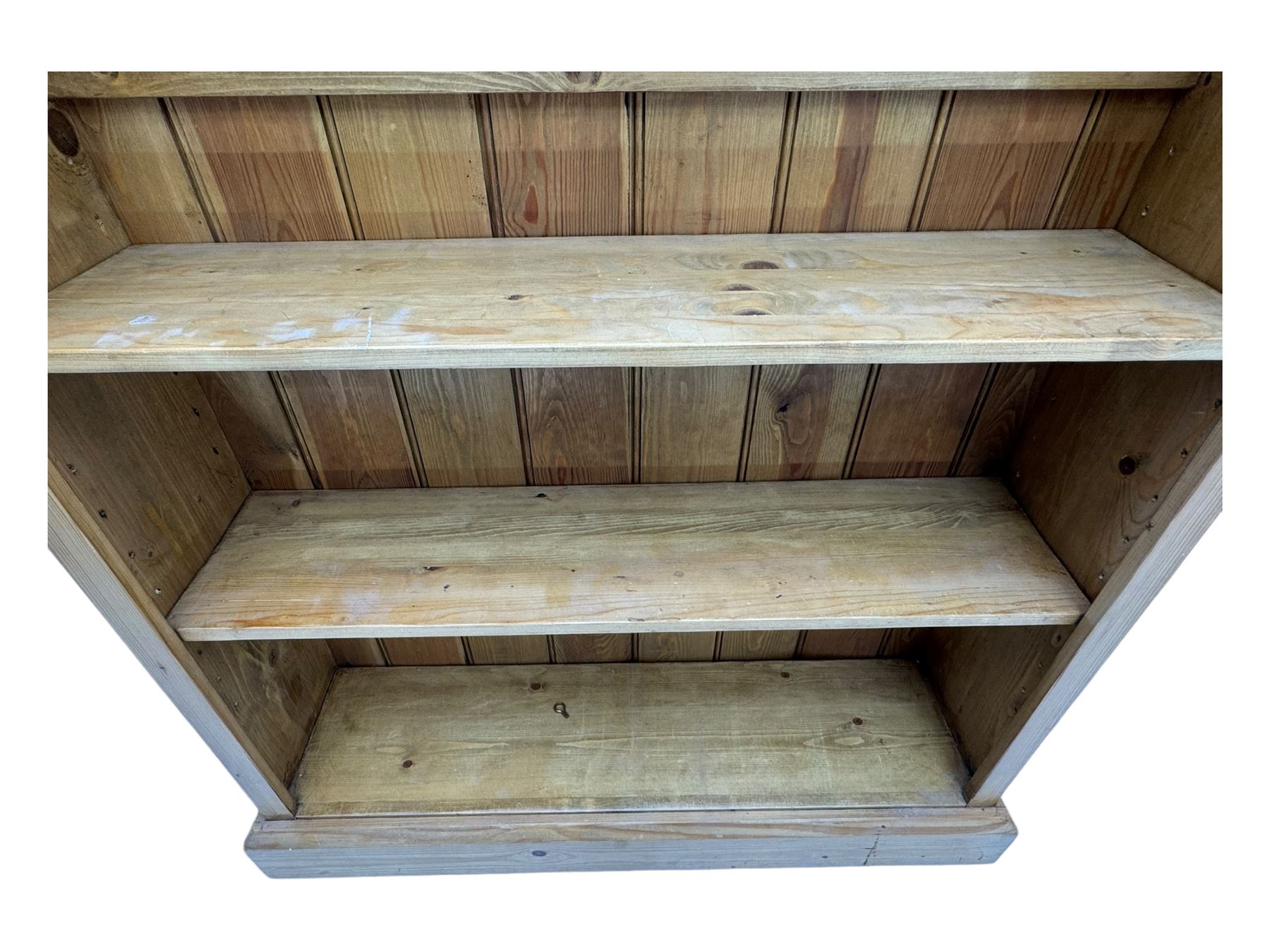 Pine open bookcase, projecting moulded cornice over arched frieze, fitted with four adjustable shelves, on plinth base