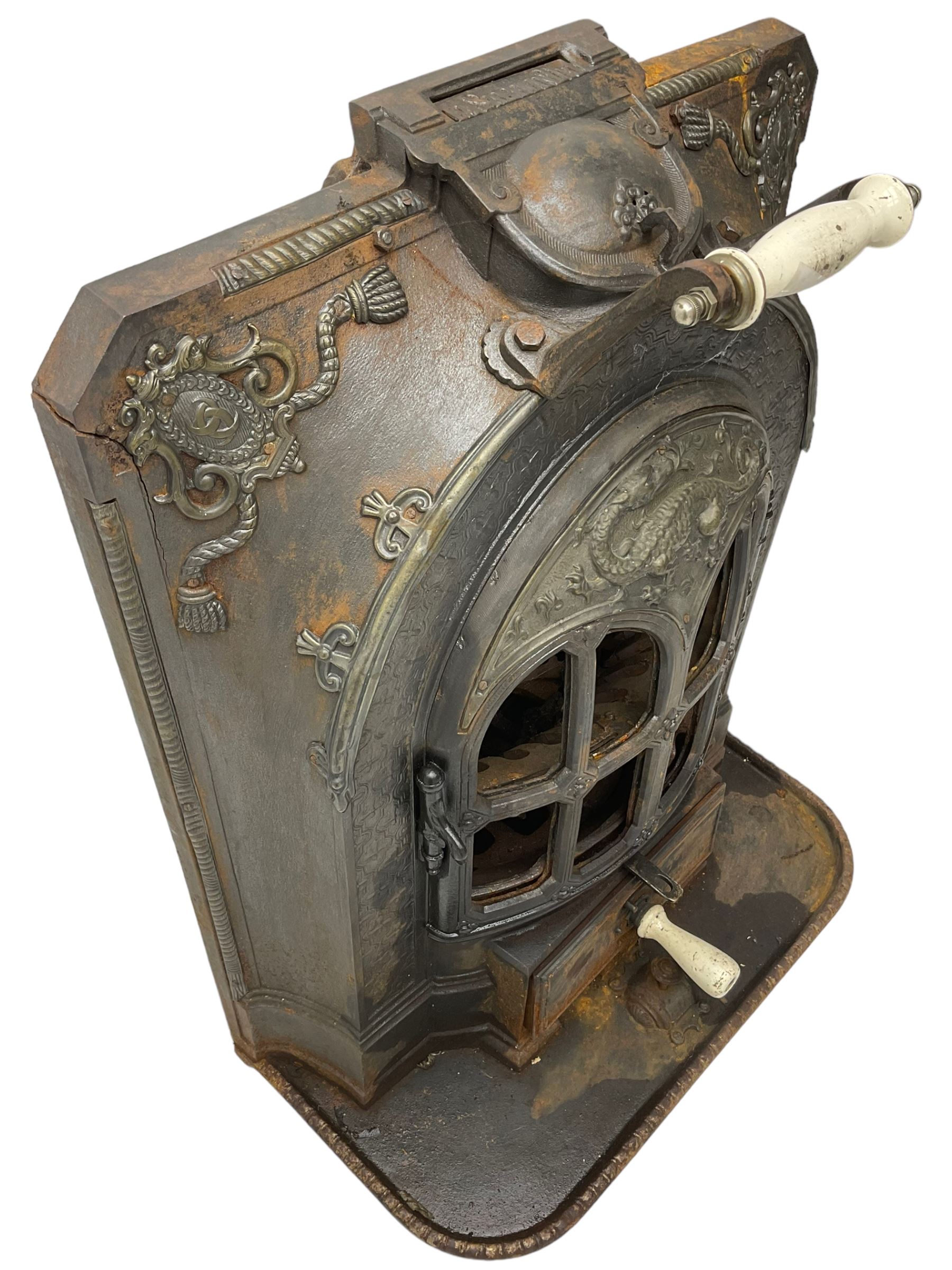 La Salamandre - early 20th century cast iron wood burning stove, decorated with salamander and cartouche motifs, fitted with porcelain handle, on rear castors 