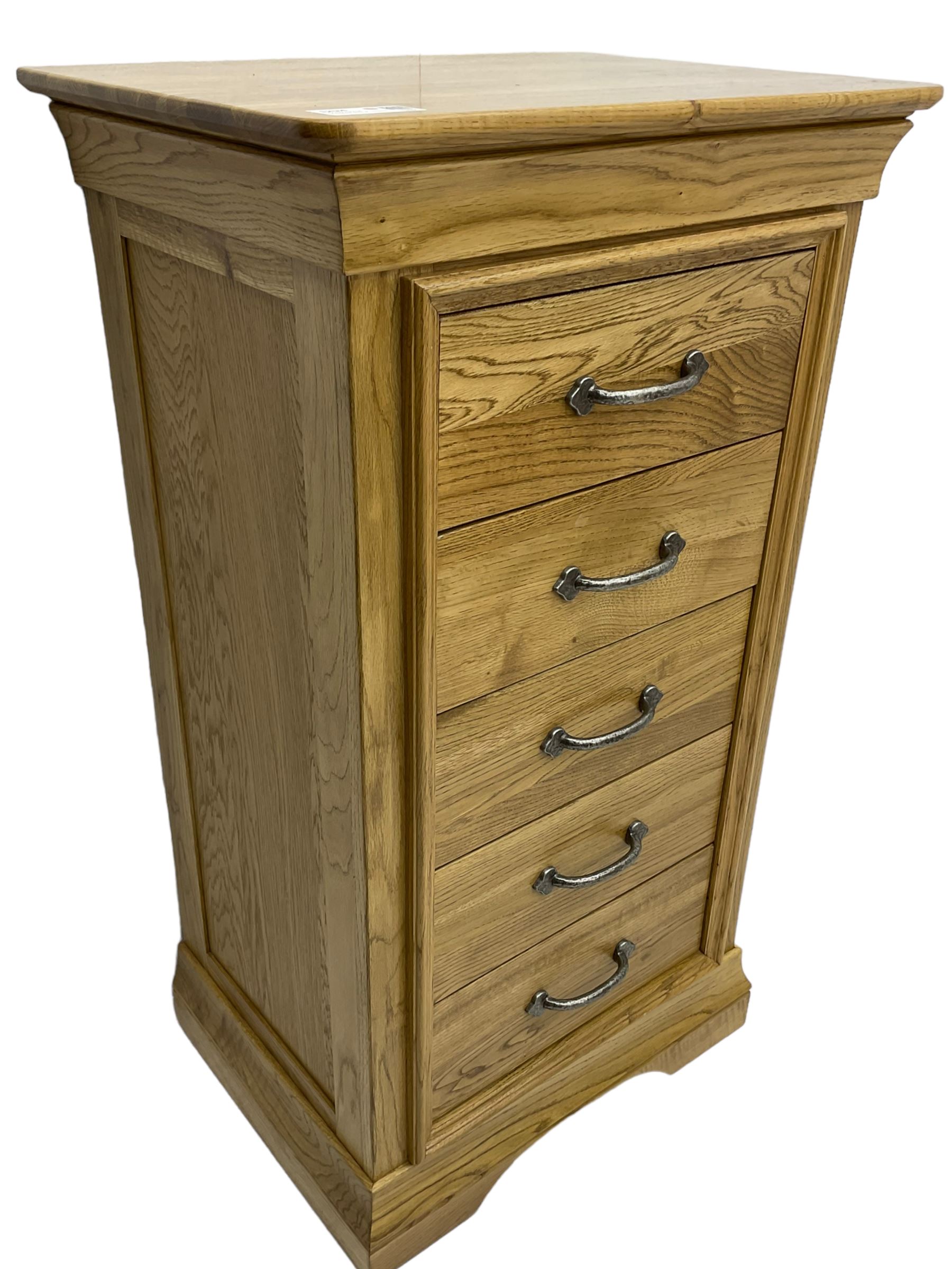 Contemporary light oak pedestal chest, moulded cornice and chamfered rectangular top with rounded fronts, over five drawers with metal handles and cock-beaded surrounds, on bracketed plinth base