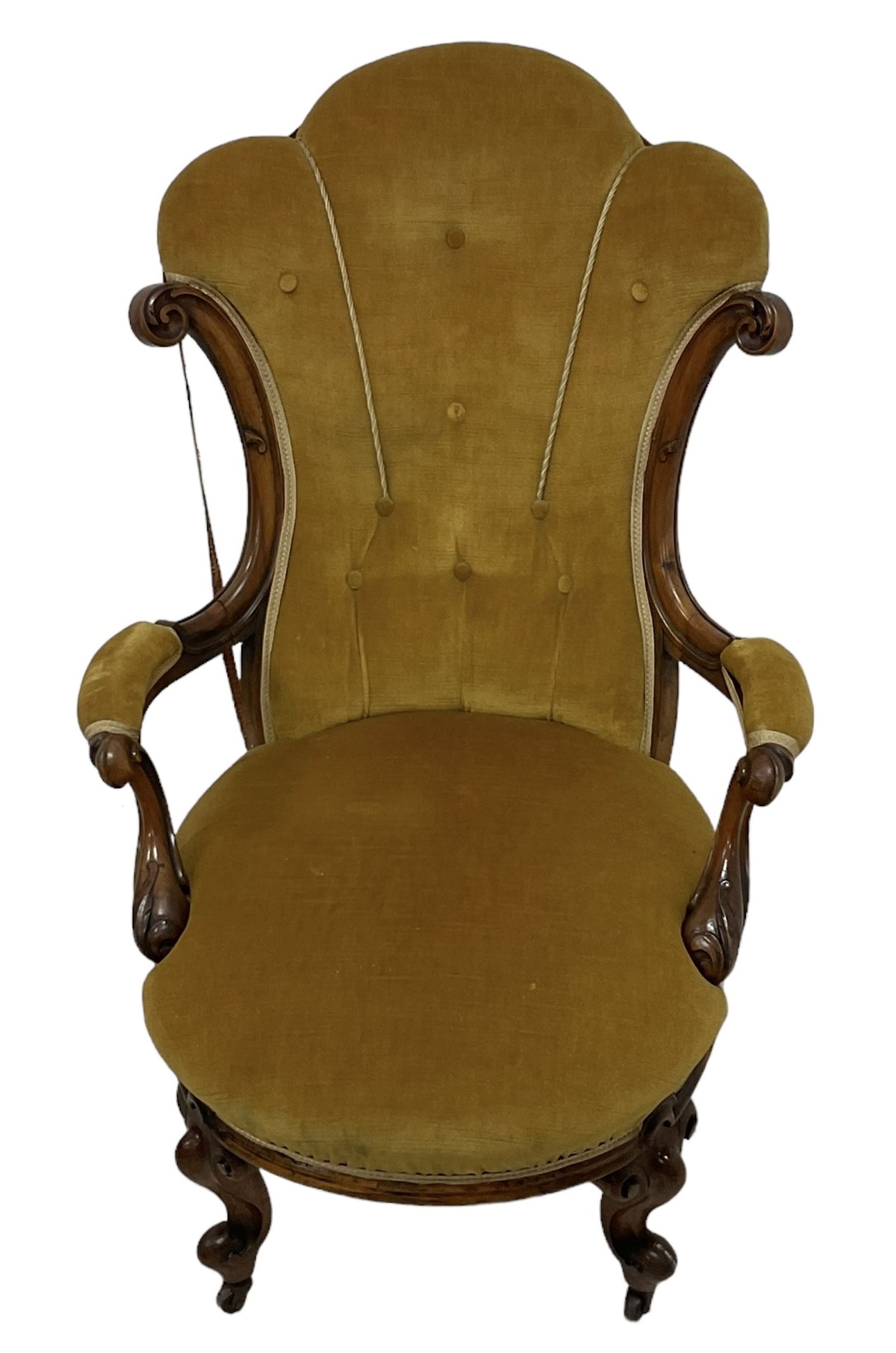 19th century walnut framed open armchair, scallop shaped back with c-scroll uprights, upholstered in yellow buttoned velvet fabric with sprung seat, arm terminals carved with acanthus leaves, raised on scrolling cabriole supports with castors